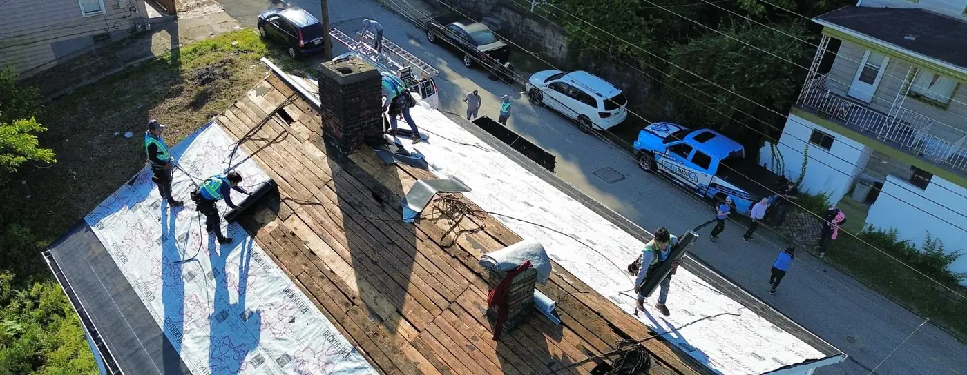 Drone aerial view of a Home Genius Exteriors roofing crew working on a residential roof, the perspective a drone roof inspection captures