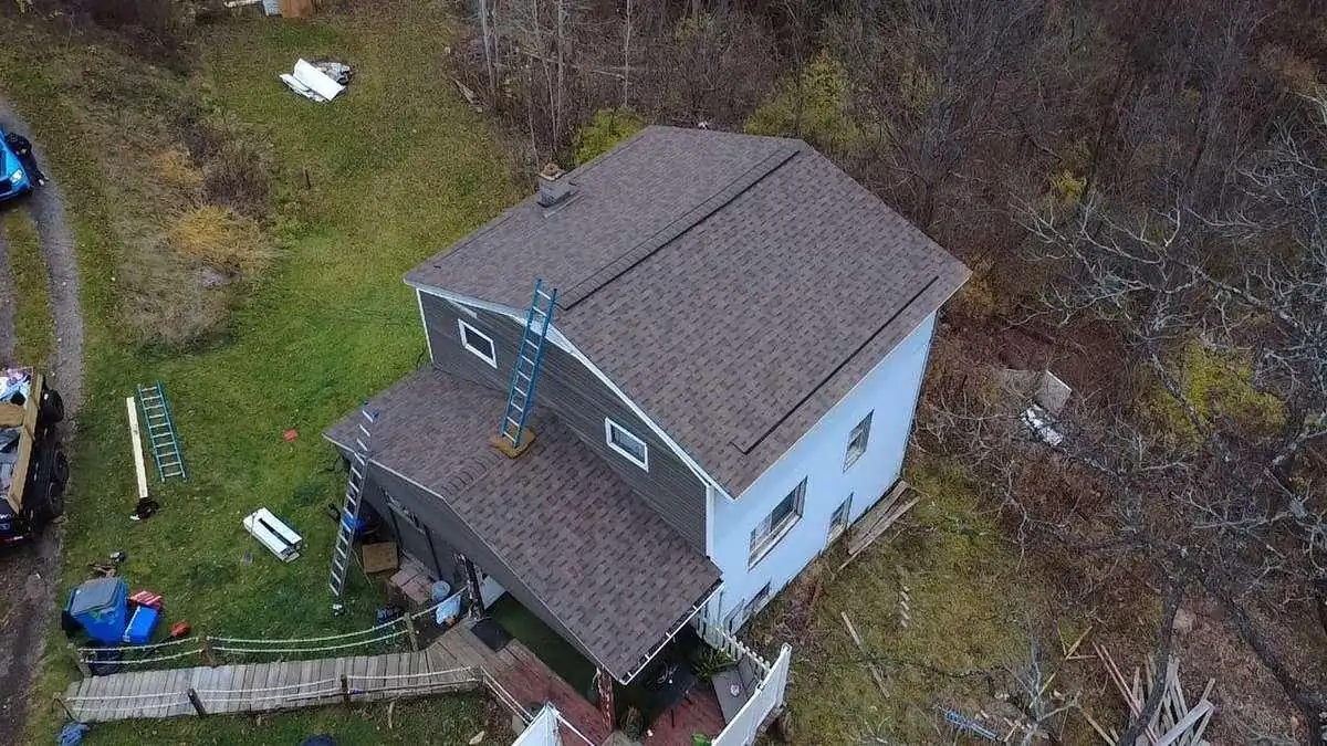 A steep gabled roof with ladders set against it shows why some roofs are safer to survey from the air.