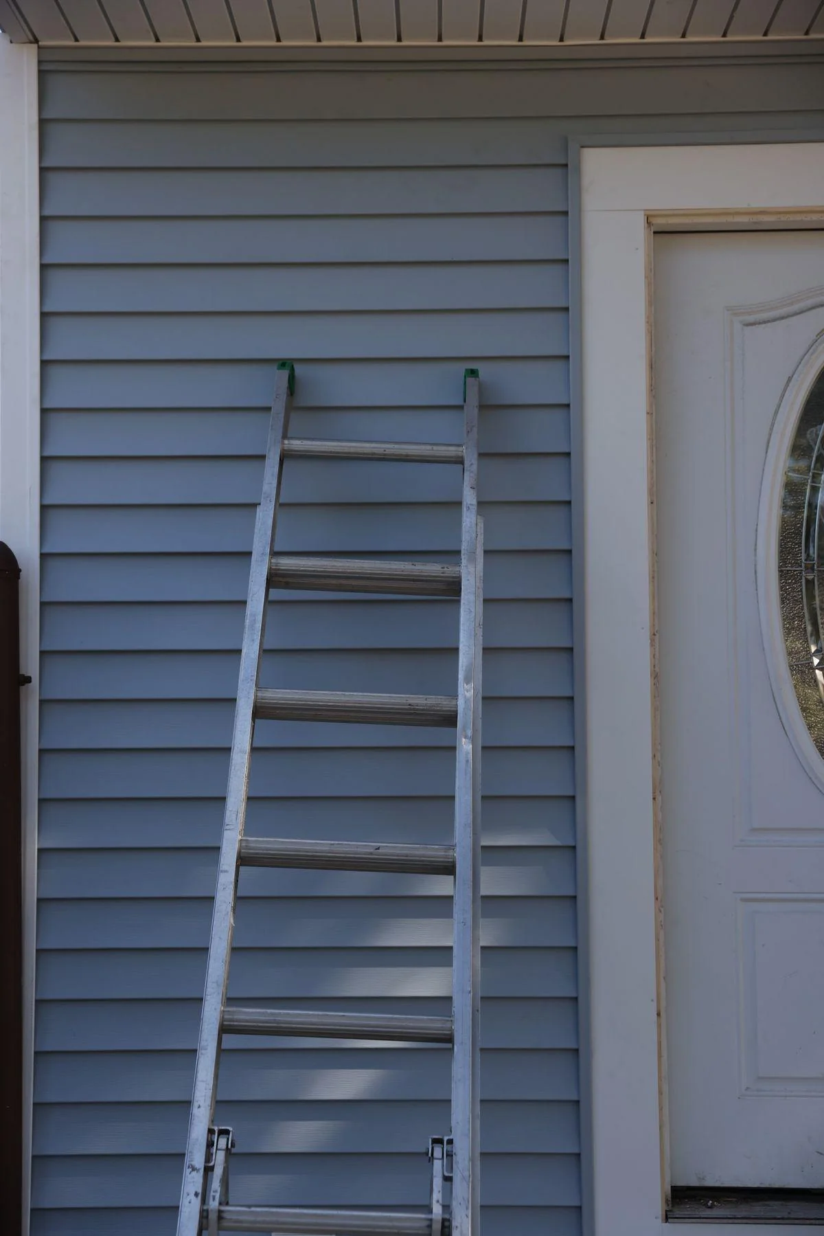 A new front door with an oval glass insert sits in fresh trim during a frame replacement.
