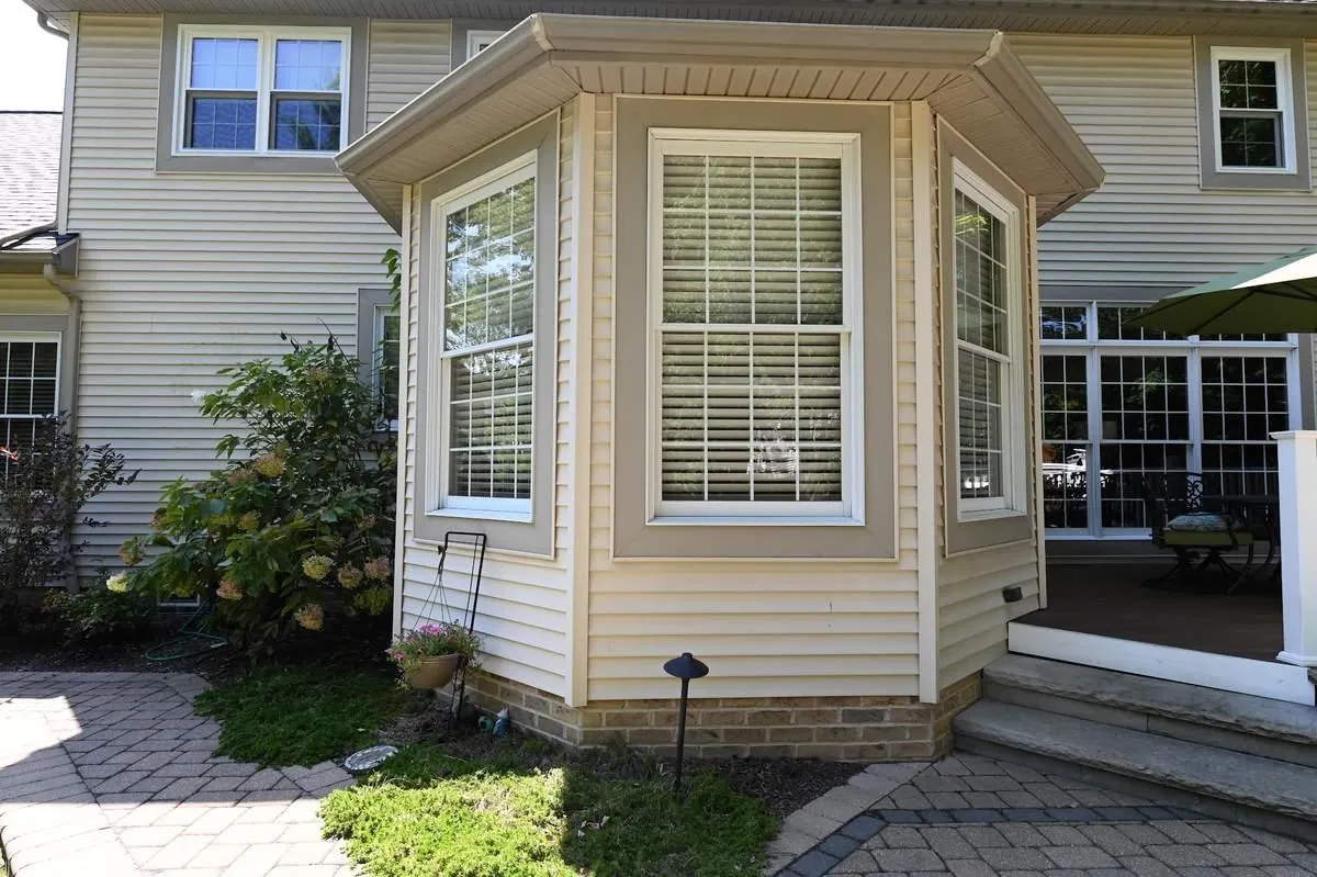 A three-panel bay window projects from a home's siding, its center pane flanked by two angled double-hung sidelites.