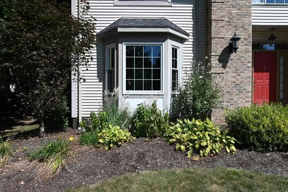 A three-sided bay window with its own small roof projects from a home's corner, a wide center pane between two angled side windows.