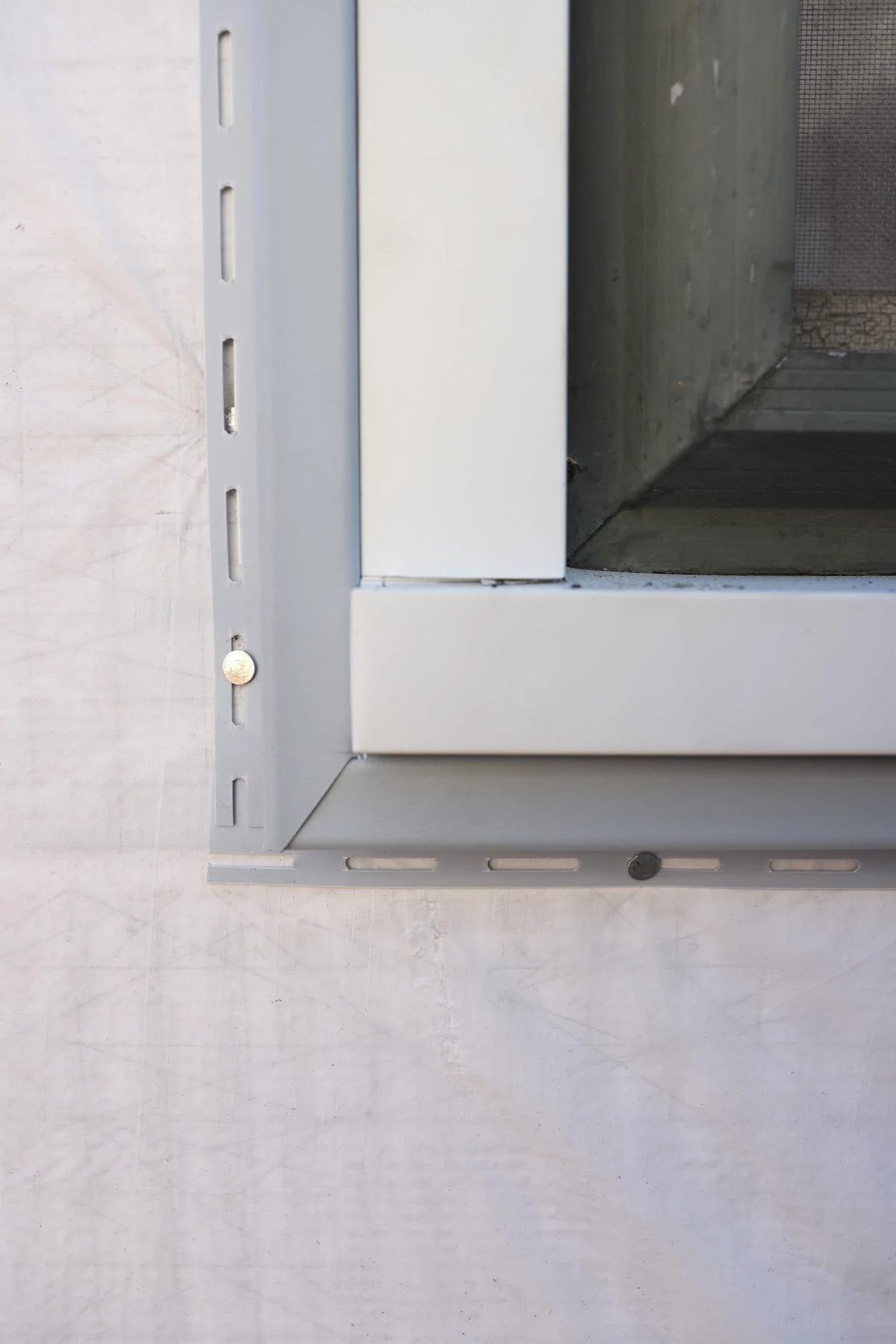 A close view of a window's white PVC corner trim shows the extruded vinyl material most replacement frames use.