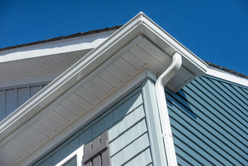 Closeup Of White Gutter System On Home With Blue Green Vinyl Siding
