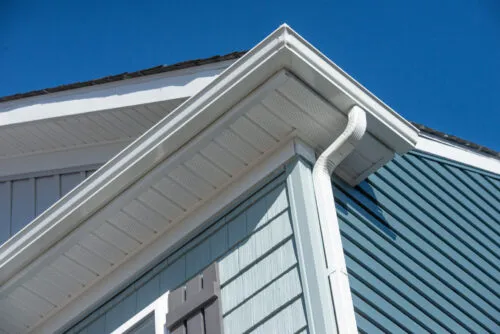 Closeup Of White Gutter System On Home With Blue Green Vinyl Siding