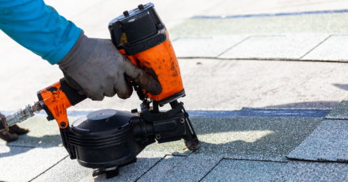 Roofer Nailing Asphalt Shingles With Nailgun