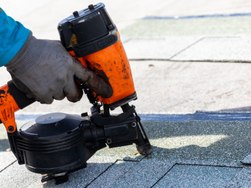 Roofer Nailing Asphalt Shingles With Nailgun