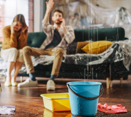 Couple on the phone calling for help while their ceiling leaks during a storm