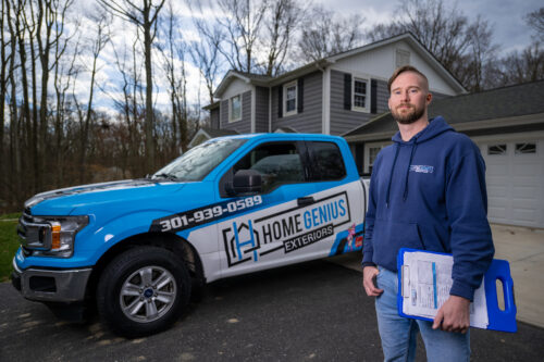 HGE home remodeling expert standing with clipboard and wrapped truck