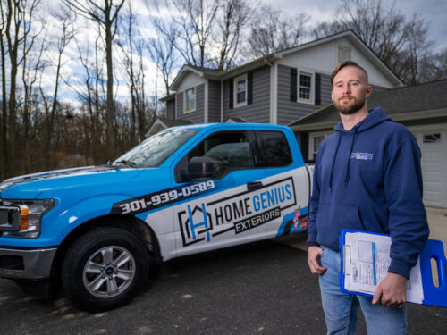 HGE home remodeling expert standing with clipboard and wrapped truck