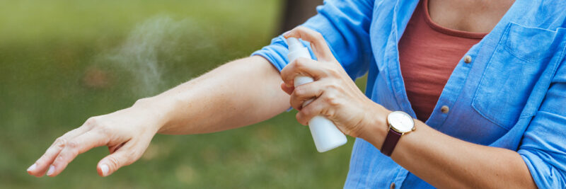 woman spraying mosquito repellant