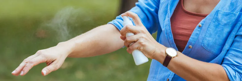 woman spraying mosquito repellant