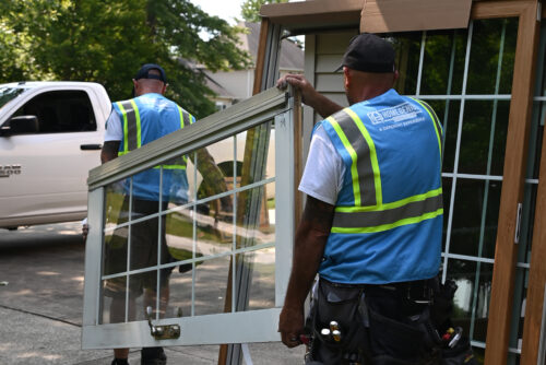 Two HGE team members carrying an exterior patio door for replacement