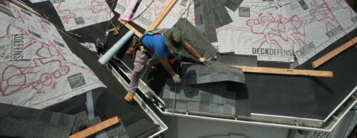Home Genius Exteriors contractor installing asphalt roofing panels