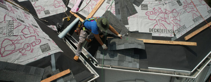 Home Genius Exteriors contractor installing asphalt roofing panels