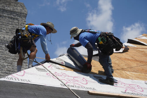 contractors laying down protective barrier material during a roof remodel