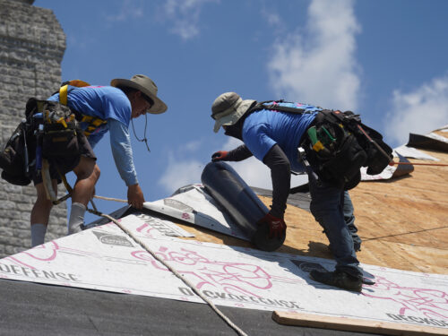 contractors laying down protective barrier material during a roof remodel