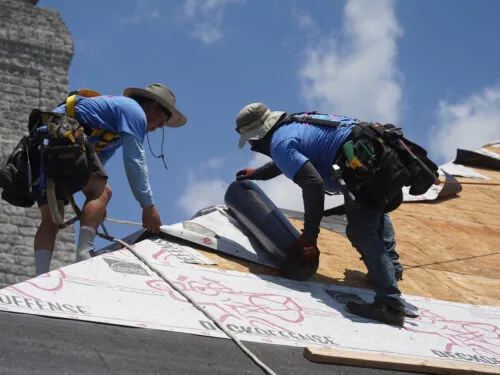 contractors laying down protective barrier material during a roof remodel