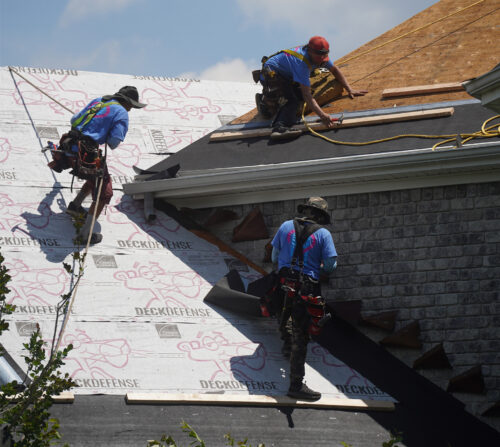 three Home Genius contractors working on a grey shingle roof