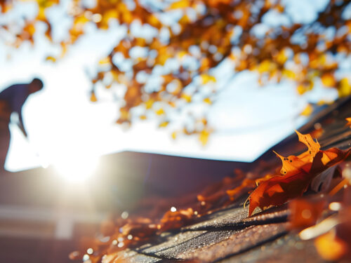 roofer on a home during fall with leaves falling