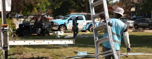 HGE Install Technician carrying ladder on a job site