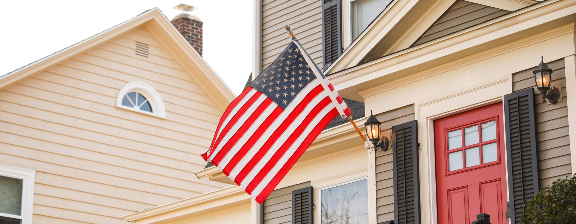 close up of a suburban home flying an American flag