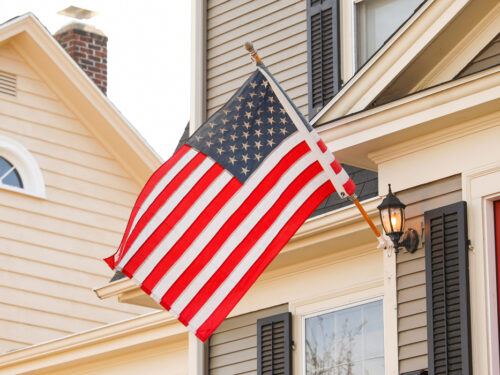 close up of a suburban home flying an American flag