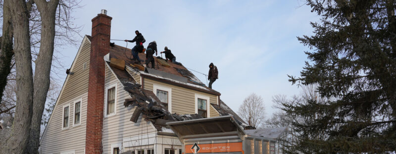 a Home Genius Exteriors crew working on the roof of a suburban home