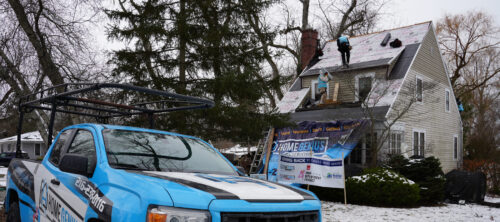 a Home Genius Exteriors pickup truck at the site of an active roof installation