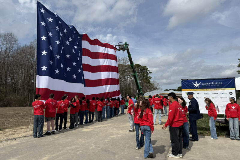 ceremony honoring U.S. Veteran with the raising of a large American flag