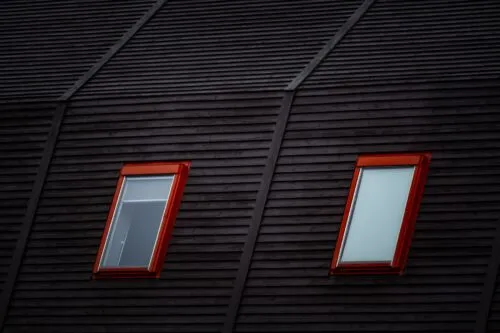Two red-trimmed skylight windows set into a dark sloped roof.