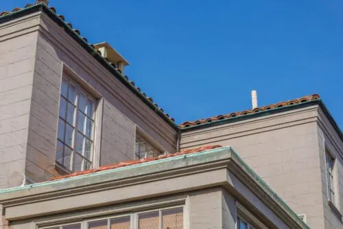 Close view of a residential building's roofline and upper exterior against a clear blue sky