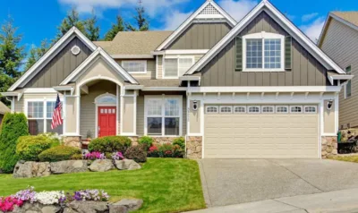 A red front door anchors the entry of a two-story home with stone accents and a landscaped yard.