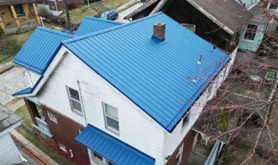 A bright blue standing-seam metal roof covers this two-story home, illustrating how long a well-installed metal roof can last.